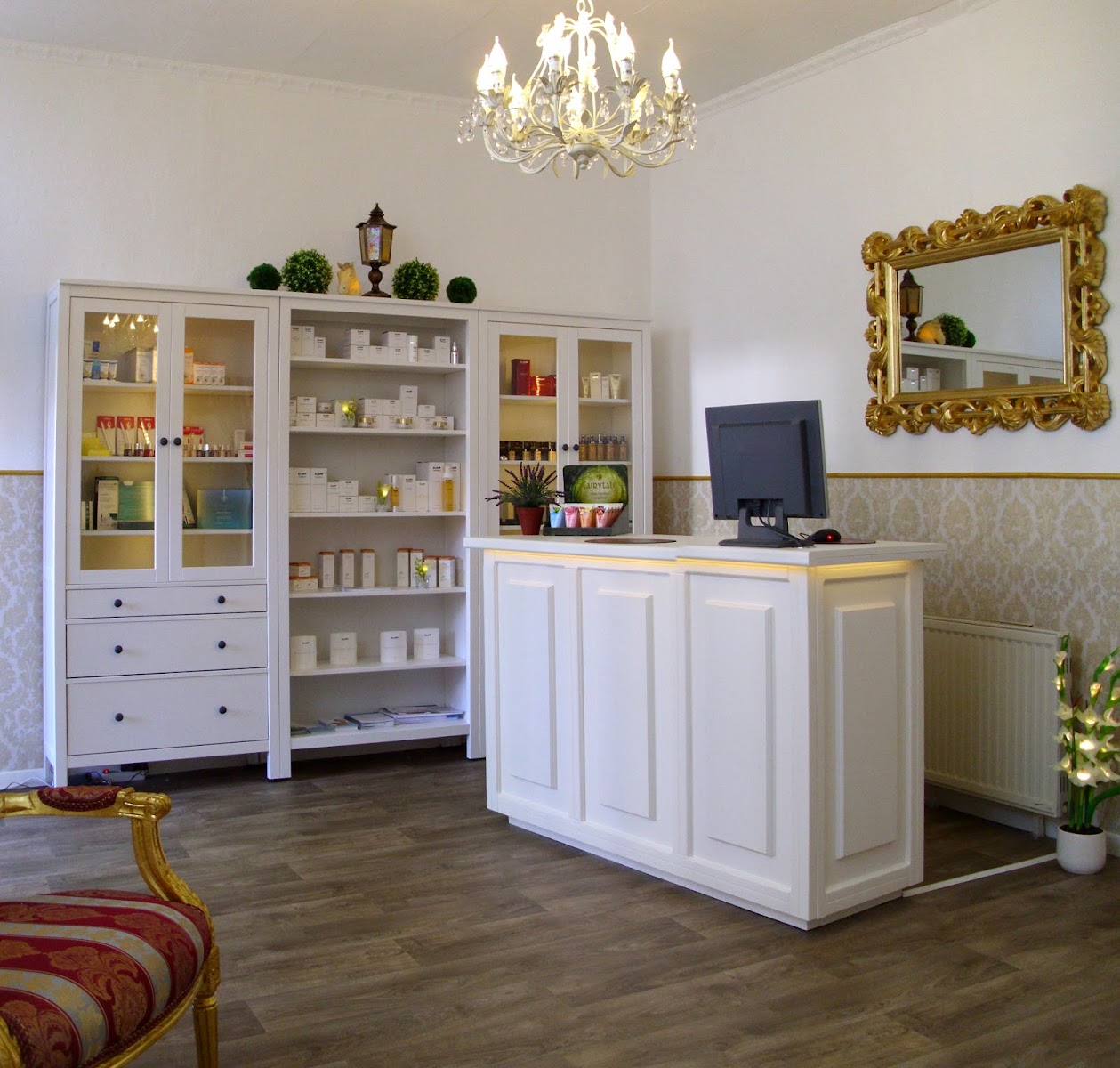 Empfangsbereich im Kosmetikstudio Regina mit Produktvitrinen und Kronleuchter