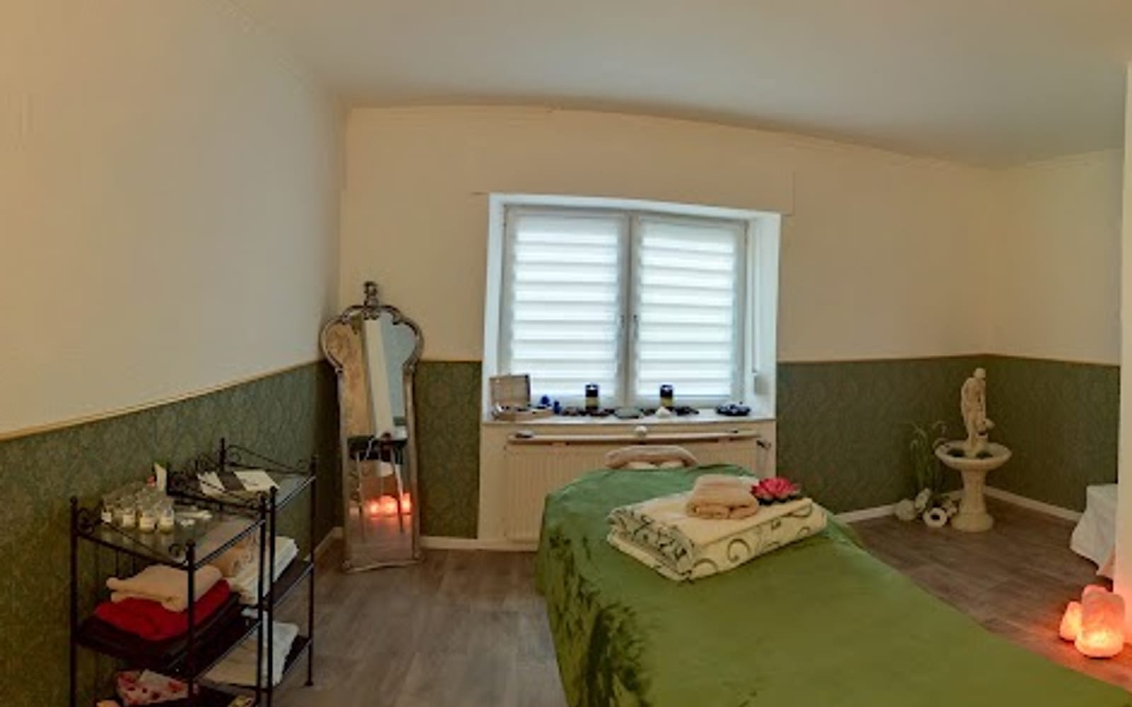 Ruhiger Behandlungsraum mit Fenster, grüner Liege und warmem Licht